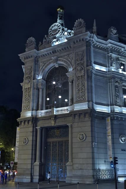 Exterior view of the Banco de España building in Madrid illuminated at night.