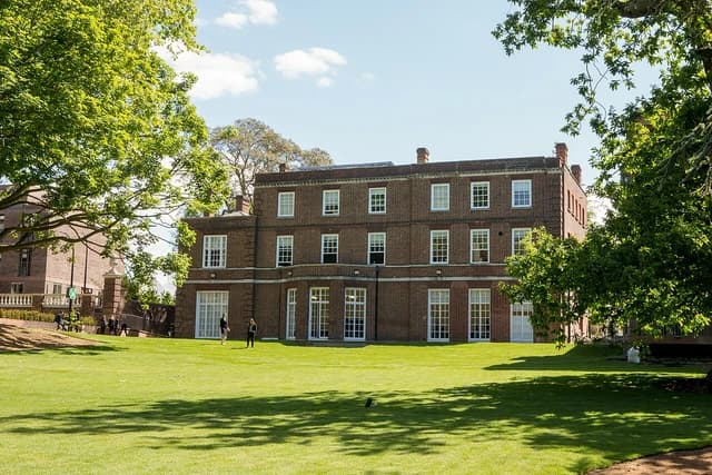 GIHE London Campus building with a manicured green lawn in front on a sunny day.