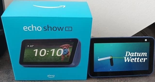 Amazon Echo Show 5 device displaying time and temperature next to its blue box.
