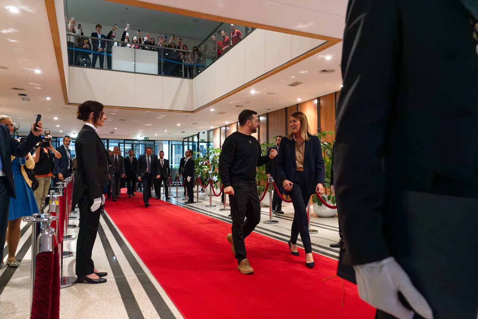Ukrainian President Volodymyr Zelenskyy walks with European Parliament President Roberta Metsola on a red carpet.