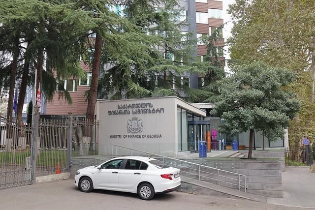 Building of the Ministry of Finance of Georgia with a white car parked in front.