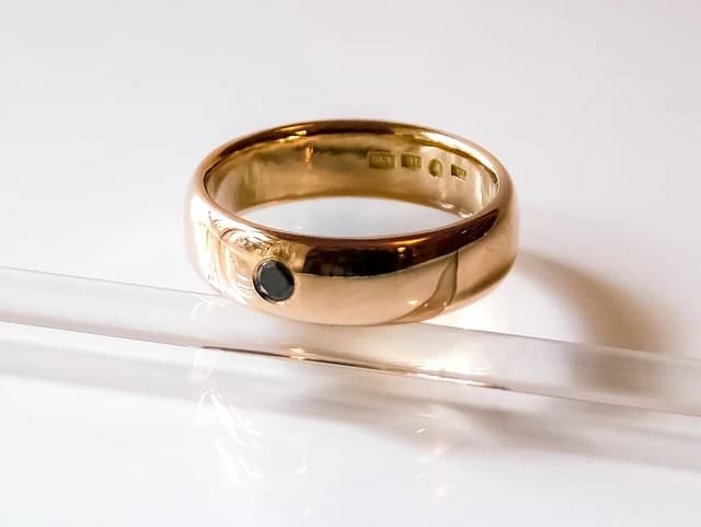 Domed gold ring with a single black diamond on a white background.
