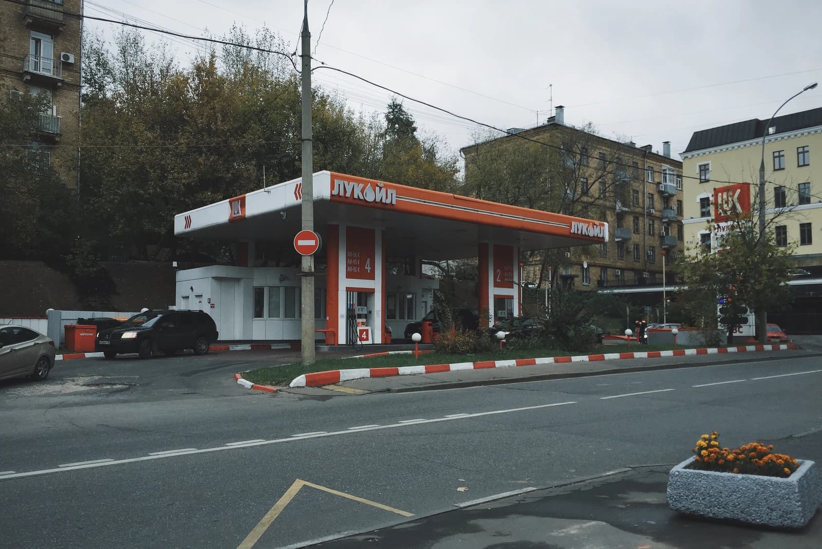 A Lukoil gas station in Moscow with multiple pumps and cars, viewed from across the street.