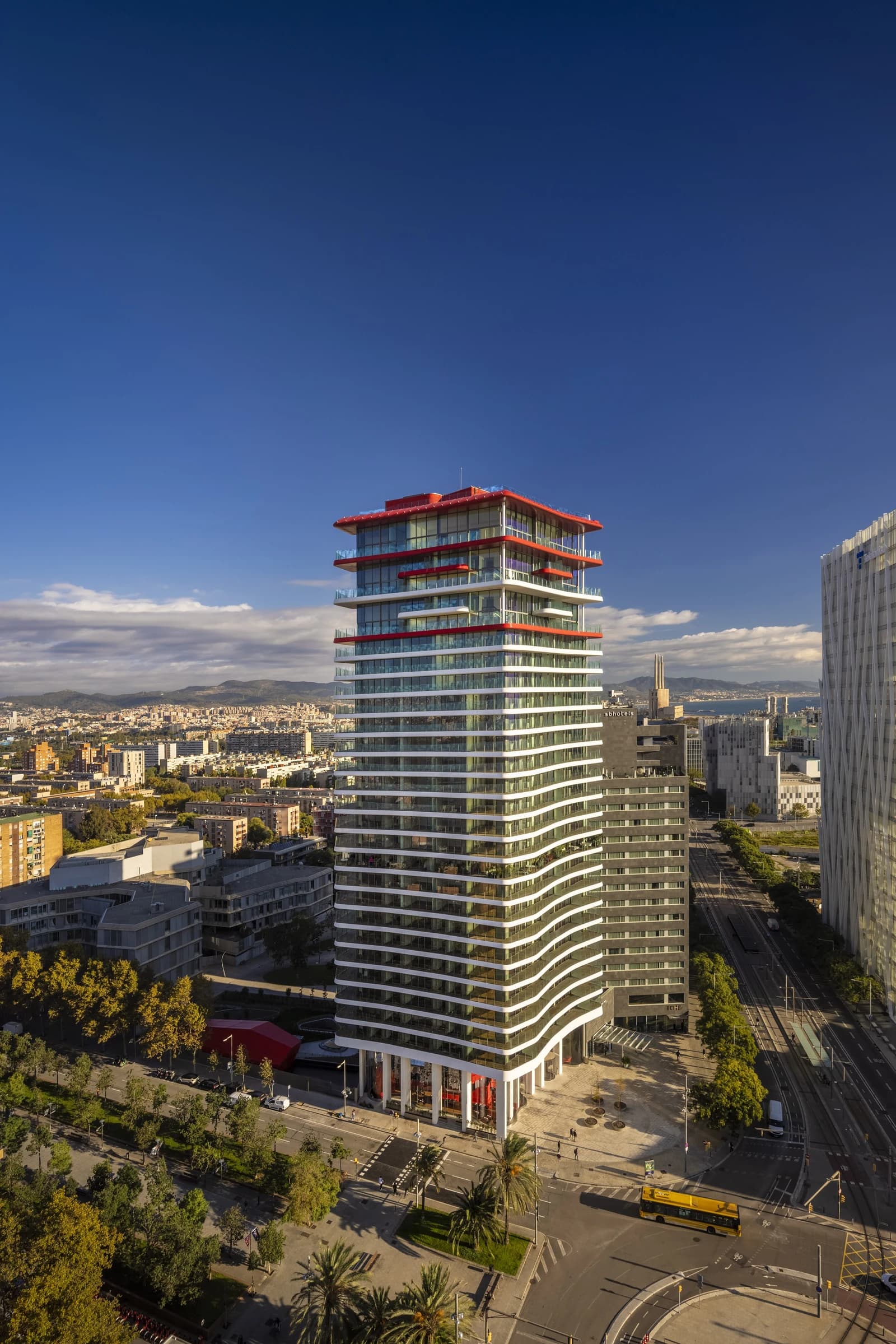 Antares Barcelona residential tower, designed by Odile Decq, standing tall amidst city buildings.