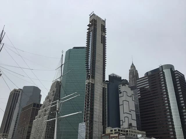 View of the Lower Manhattan skyline with several skyscrapers under a gray sky.