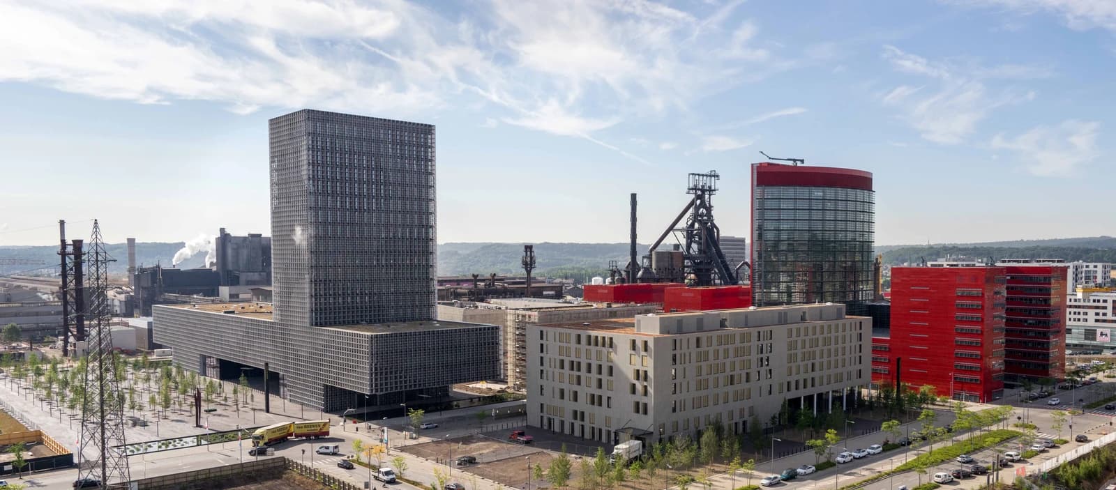 Aerial view showing multiple modern buildings on the Belval Campus, University of Luxembourg, under a blue sky.