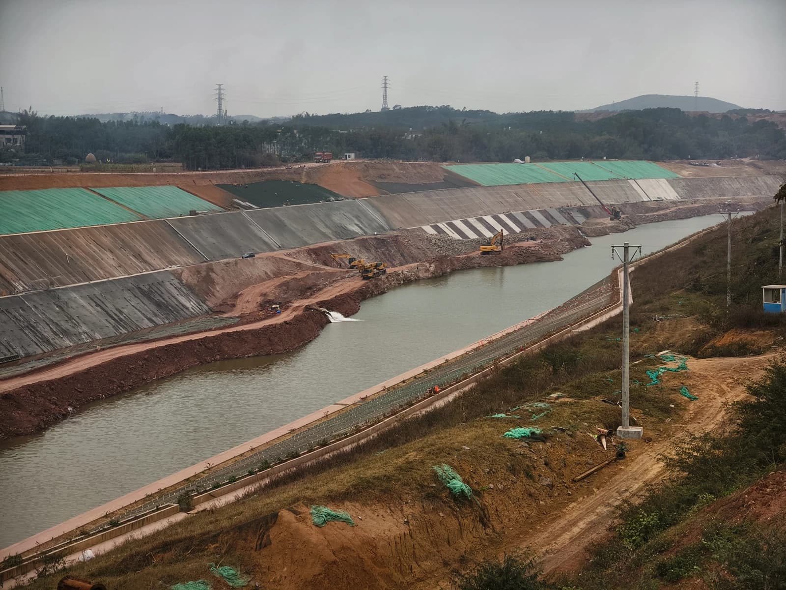 An overview of the Pinglu Canal under construction, showing excavators and water flowing.