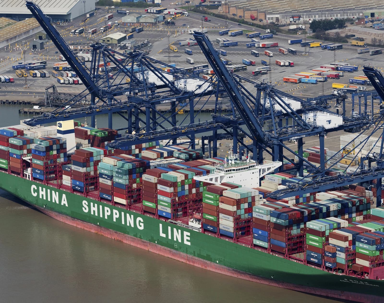 The container ship CSCL Indian Ocean is docked at a port with large cranes.
