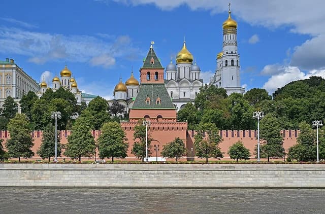 Moscow Kremlin viewed from across the Moskva River under a blue sky.