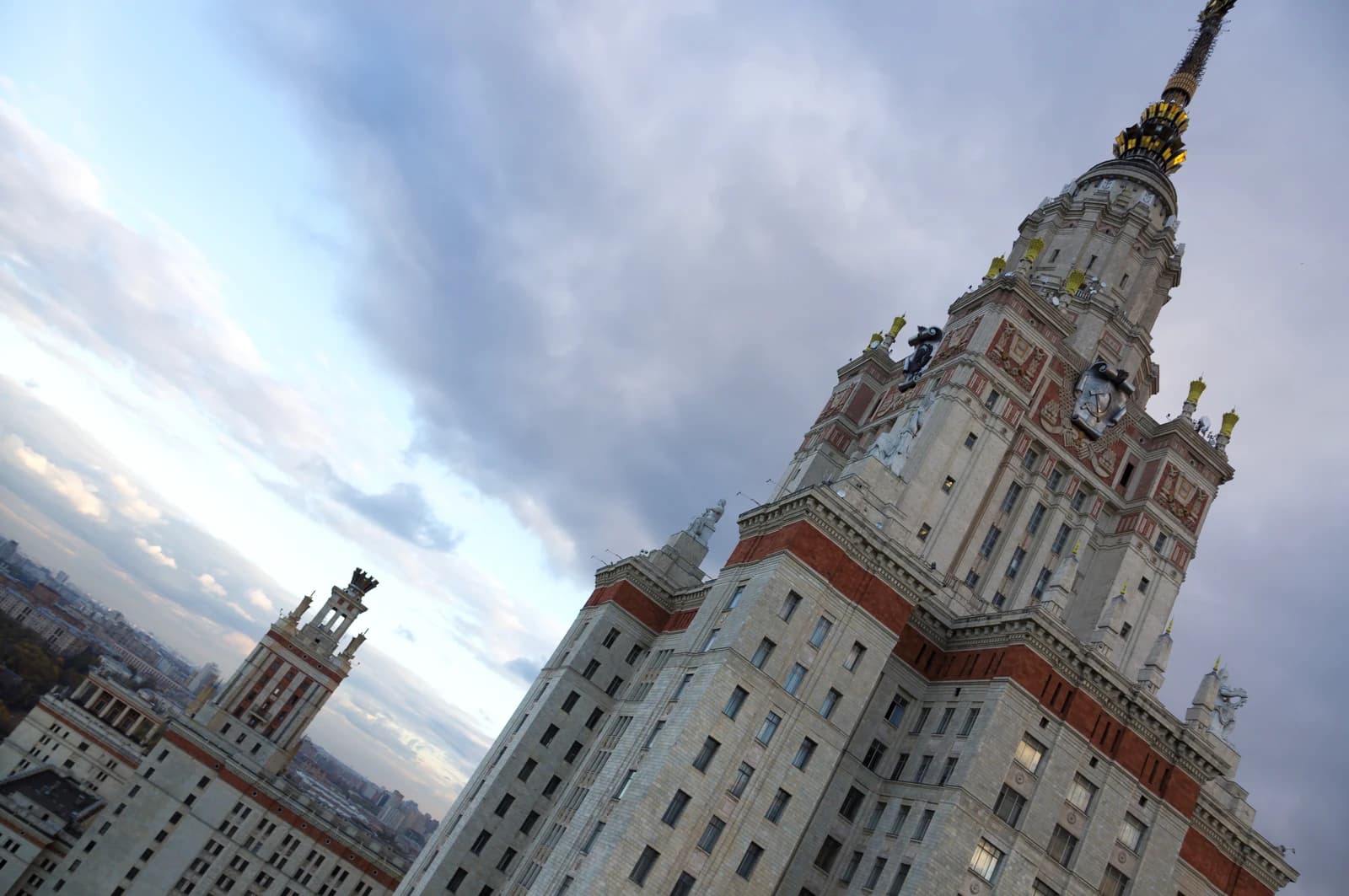 Moscow State University's main tower with other buildings under cloudy sky in Russia.