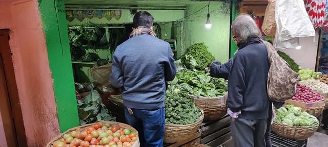People selecting fresh vegetables from baskets at a shop in Shillong, Meghalaya.