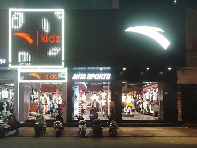 Exterior of an Anta Sports store at night, displaying the brand logo and 'kids' signage.