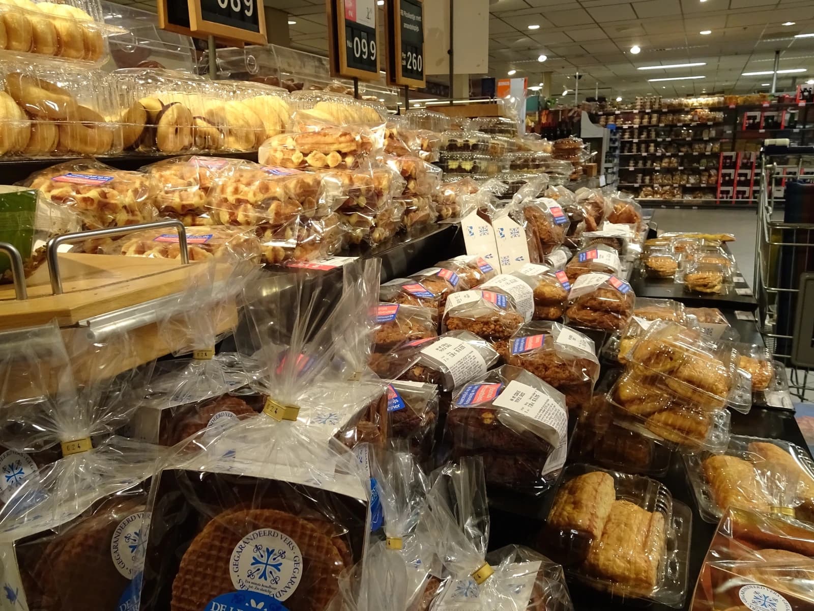 Supermarket shelf laden with various packaged bakery items and Dutch stroopwafels.