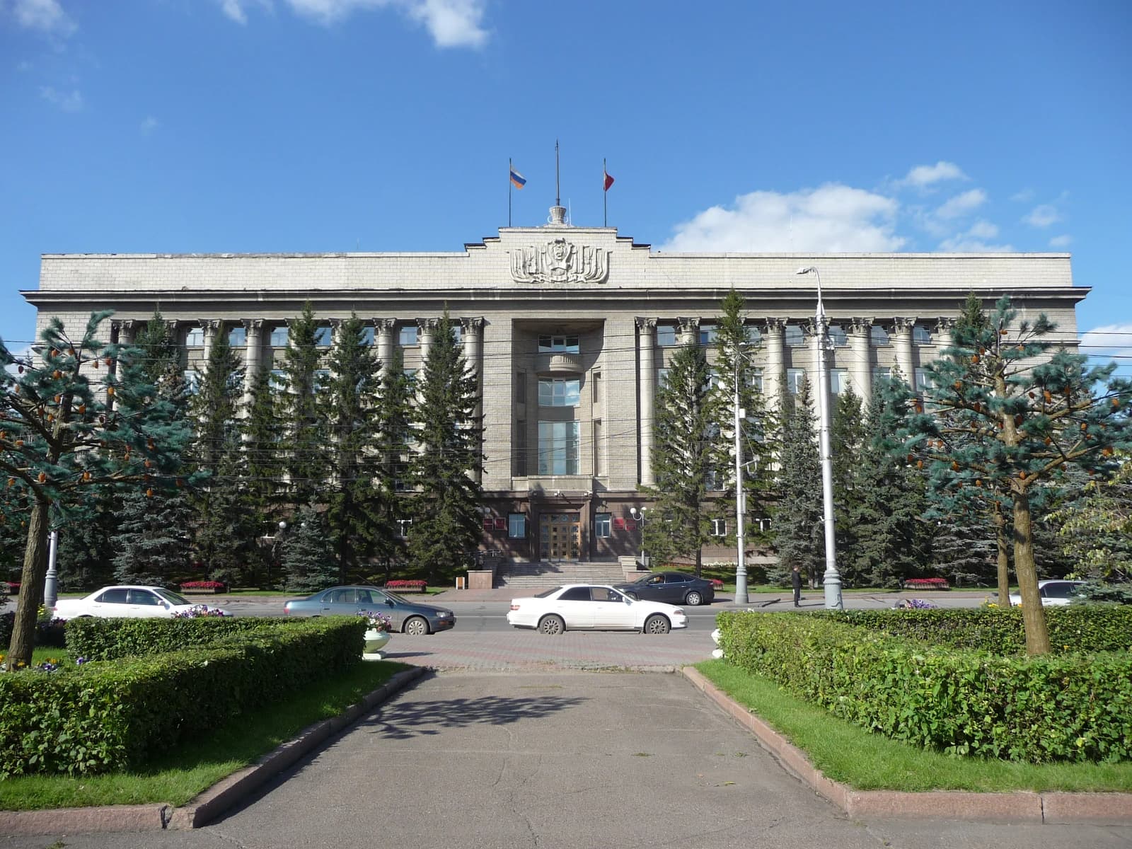 Krasnoyarsk Krai government building with columns and evergreen trees outside.