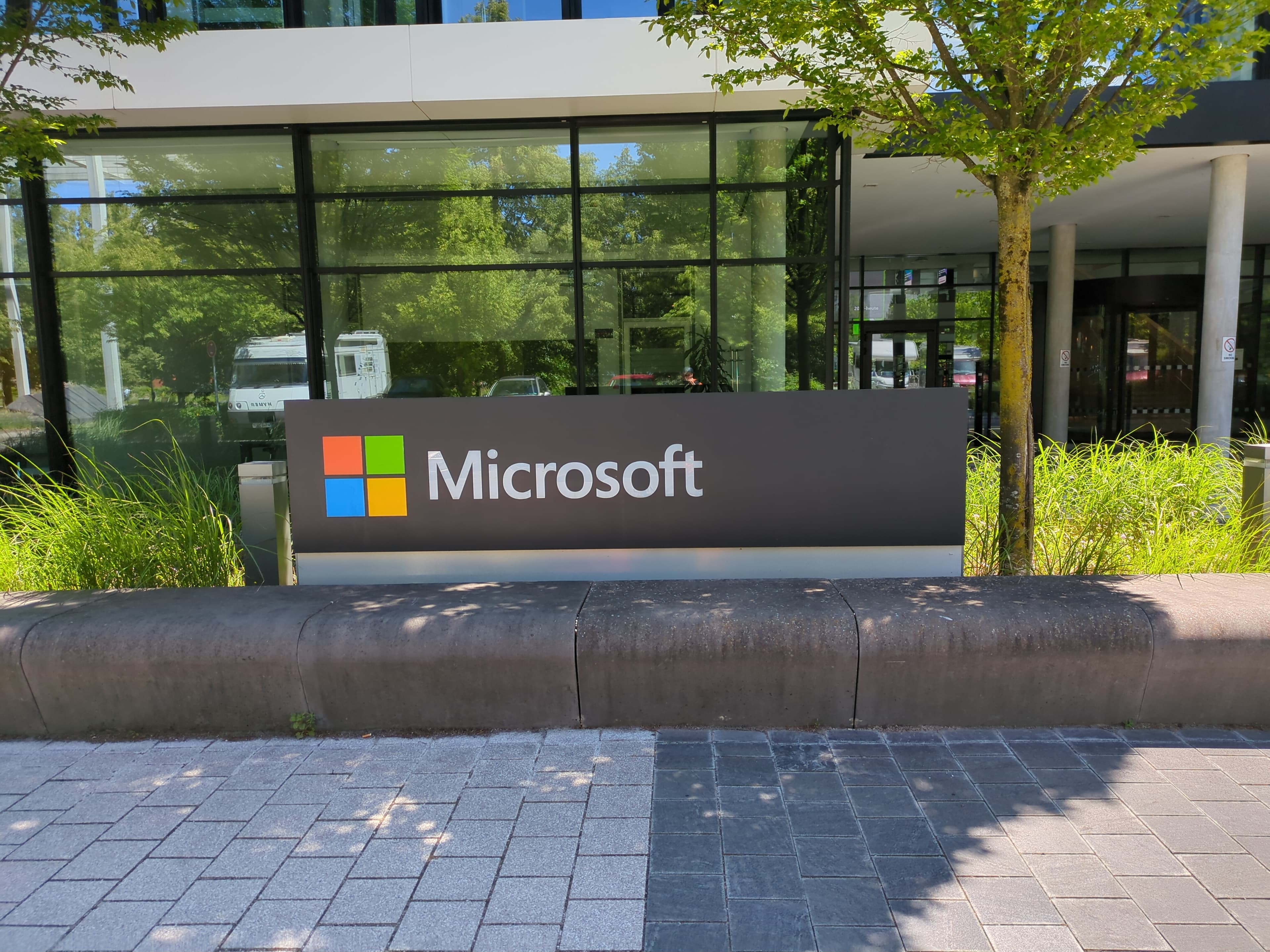 Entrance sign with Microsoft logo and building reflection at Microsoft headquarters in Munich.