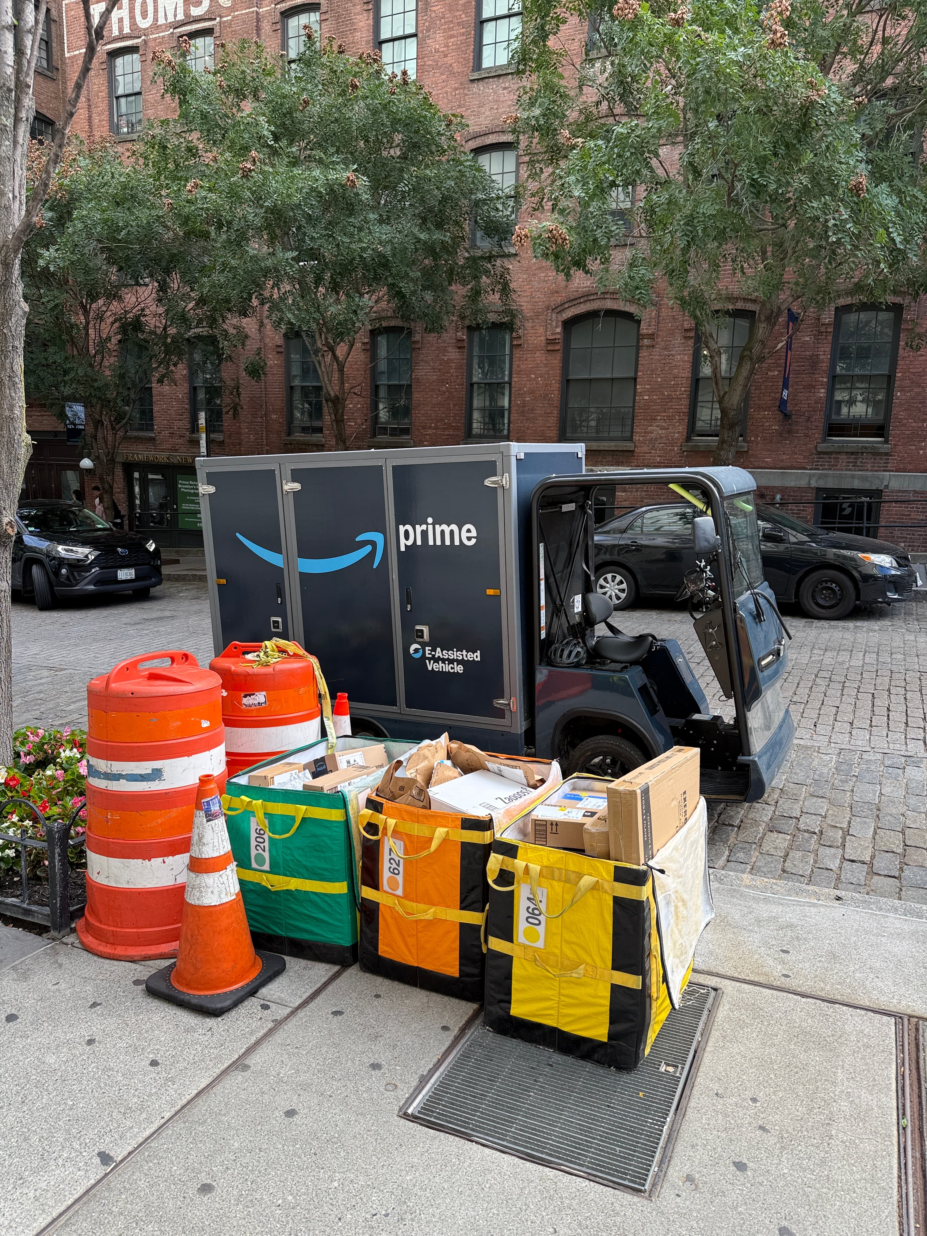Amazon Prime delivery vehicle with multiple packages in bags on a city sidewalk.