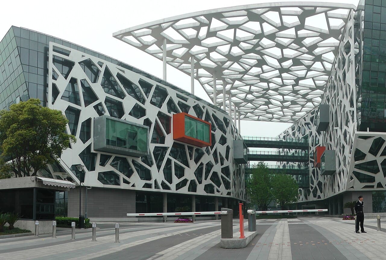 Modern Alibaba Group Headquarters building with geometric patterns and a security guard.