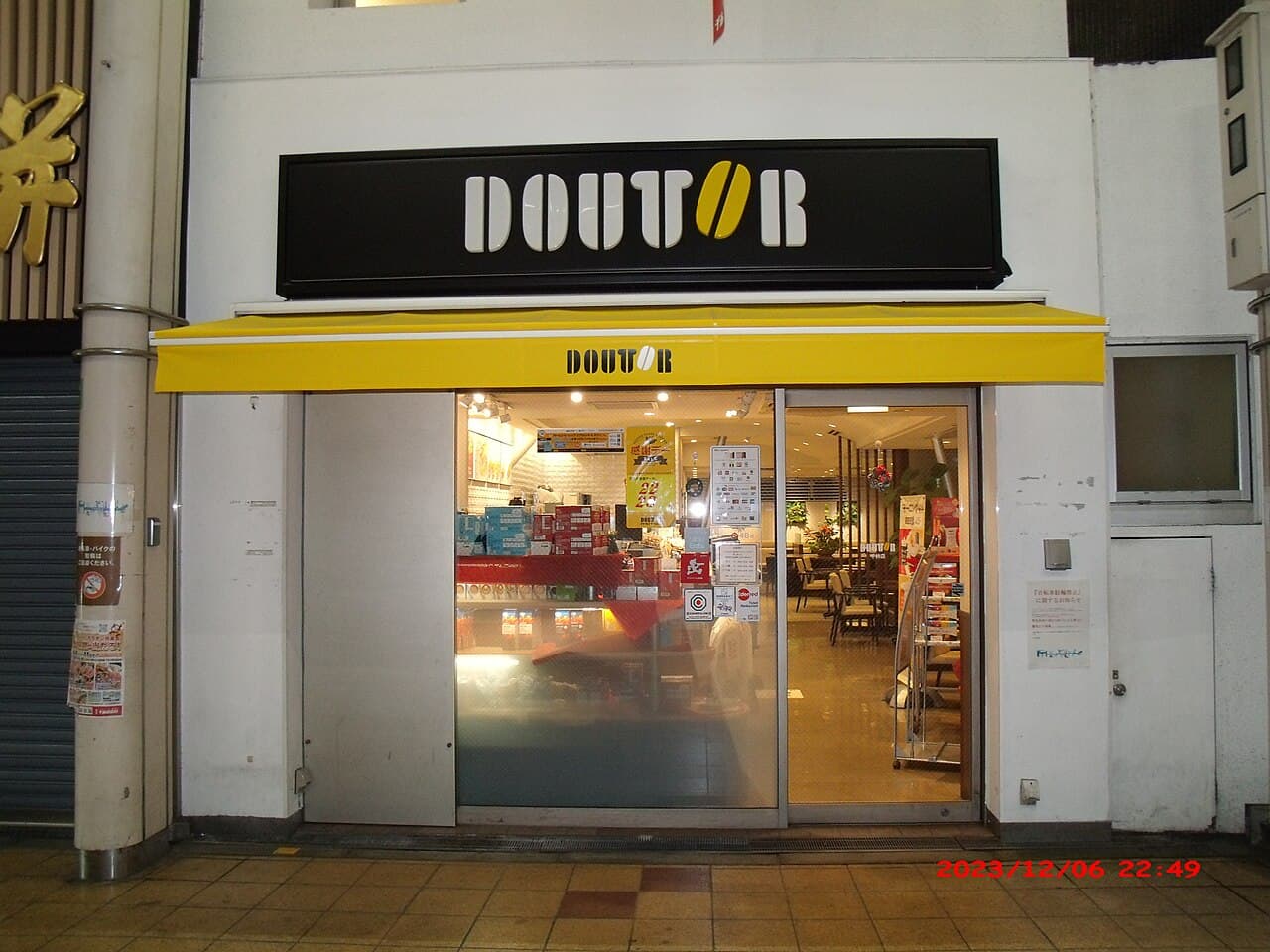 Exterior view of a Doutor Coffee shop with a yellow awning and visible interior seating.